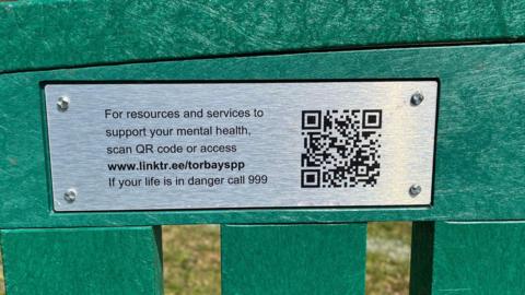 Plaques have been installed across Torbay. The plaque is attached to a green bench with details of how to get help as well as a QR code.