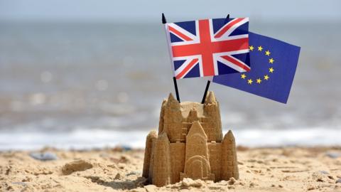 The UK and EU flags in a sandcastle