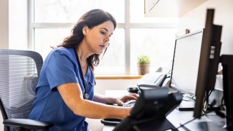 Nurse working at computer in exam room