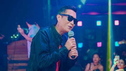 Prashant Tamang performing for his fans at a club. He is wearing a jacket, shirt and a pair of sunglasses. 