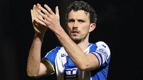 Tom Flanagan applauds spectators after a Colchester United game