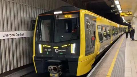 A yellow train car at Liverpool Central station platform 