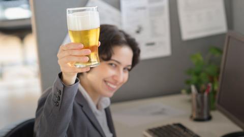 A woman holding a beer in the air in the office