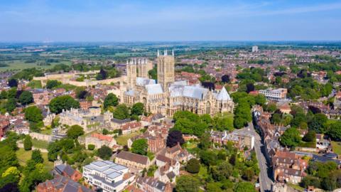 An aerial view of Lincoln Cathedral, which is surrounded by red-brick buildings and greenery