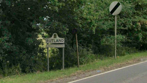 A sign which marks the start of Rutland next to a national speed limit sign