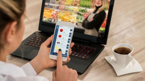A woman using a greengrocer shopping app and laptop 