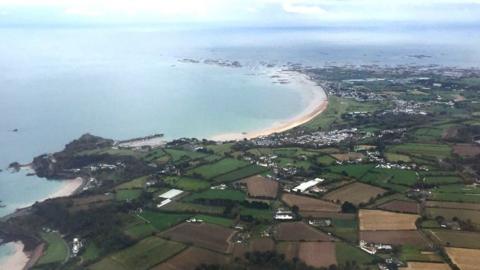 Jersey seen from a birds-eye view with sea on the left and green land on the right.