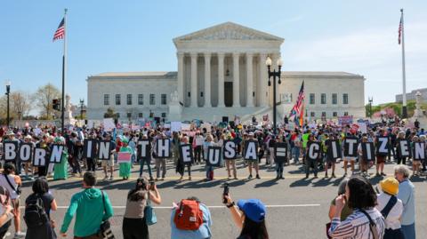 Demonstrators hold letters making up the slogan "Born in the USA = citizen!" outside the U.S. Supreme Court building 