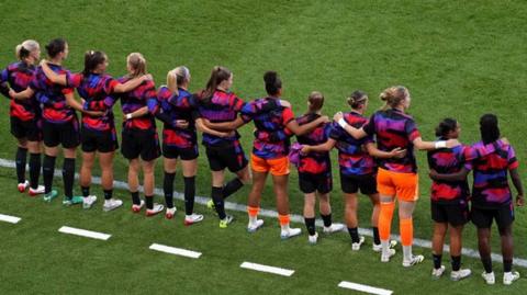England's substitutes with their hands round each other's shoulders on the touchline 