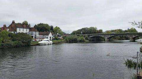 A picture of the River Thames supplied by Surrey Police. A bridge can be seen in the image alongside two buildings and a boat.