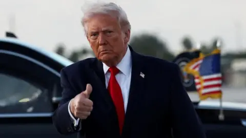 President Donald Trump gives a thumbs up as he arrives at Miami International Airport in Florida