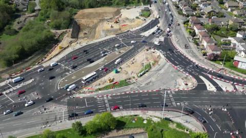 An aerial view of Dawsons Corner junction in Leeds where a new junction is being built. Fresh tarmac has been laid, but some parts of the road are still under construction.
