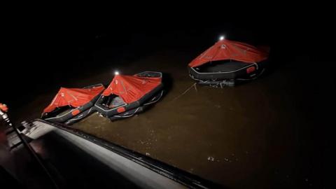 Several inflatable lifeboats in the water.