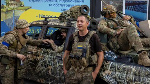 Ukrainian servicemen gather around a pickup truck in Pokrovsk, Ukraine, as they prepare to move into battle.