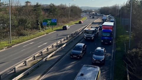 A picture taken from above the M5 motorway in Somerset. A long line of stationary traffic can be seen queuing up on one side