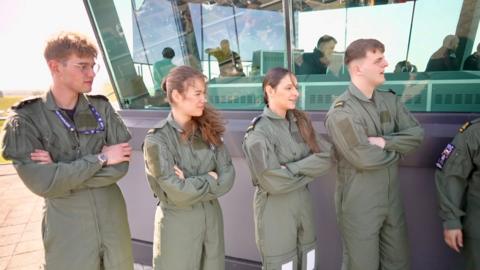 Four young people standing on an air traffic control towner balcony 