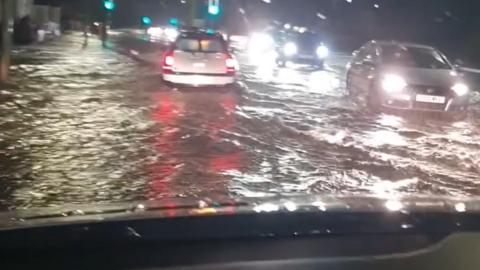 A flooded road, with cars driving through water at night