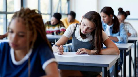 Teenage students sitting an exam paper at their individual desks