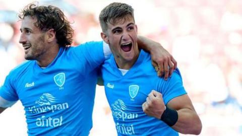 Juan Gonzalez celebrates a try for Uruguay with his arm around a team-mate