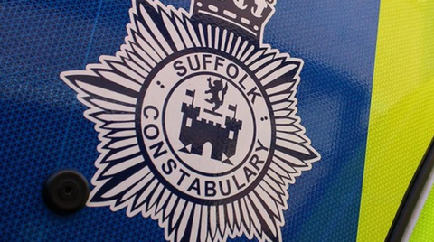 A badge of Suffolk Constabulary is shown on the side of a police car. The picture is focused on the badge, which is a circle that says Suffolk Constabulary in black writing. 