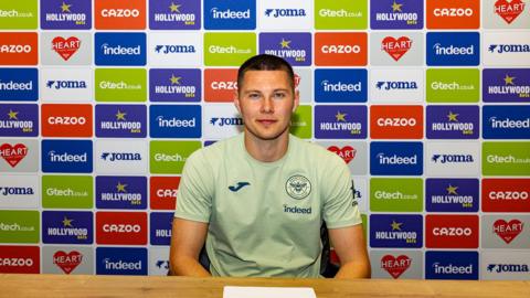  Hakon Valdimarsson sitting in front of board covered with adverts