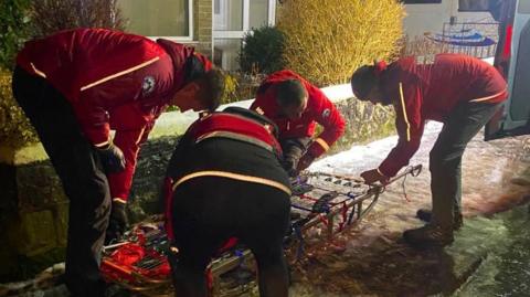 Four rescuers preparing a stretcher to be used on a frozen pavement