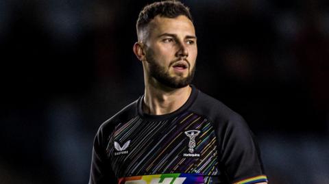 Max Green, wearing Harlequins' black kit with different coloured, diagonal pinstripes 