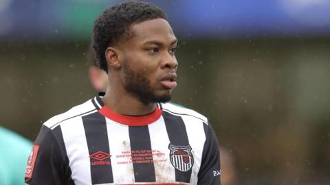 Tyrell Warren in action for Grimsby Town, wearing a black-and-white striped shirt