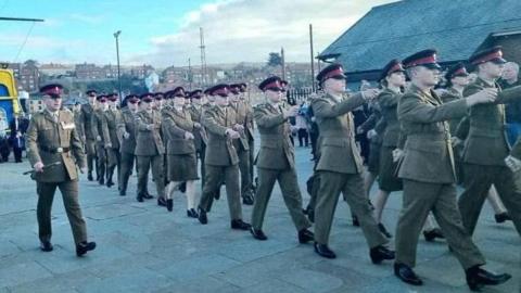 A procession of people in green Army uniforms.