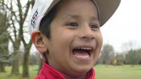 Aaron Rai close up photo, beaming smile across his face, wearing a red top and white golf cap.