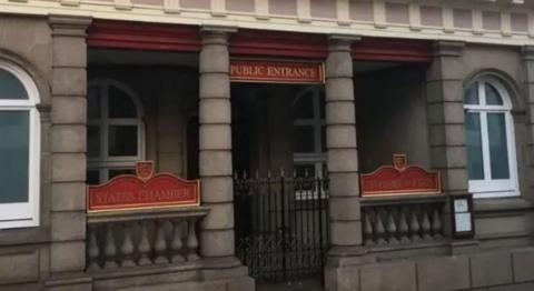 A picture of the front of the states chamber. It is a brown building with metal gates and two signs either side of the entrance  that read “states chamber”