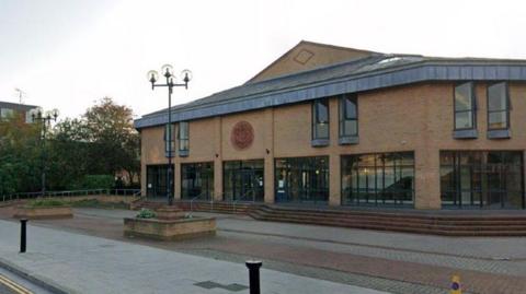 Google view of Lincoln Magistrates' Court. The building is constructed of light-coloured brick and has several large black-framed windows on the lower floor. There are steps leading up to the entrance.