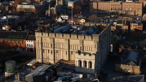 An aerial view of Norwich Castle. It's a sunny day and the building is well lit in daylight on one side.