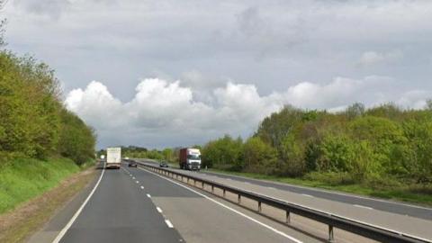 A14 road in daylight with two trucks in the distance