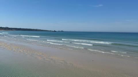 The ocean with blue skies in view, land can be seen to the left with Rocco tower in the ocean also.