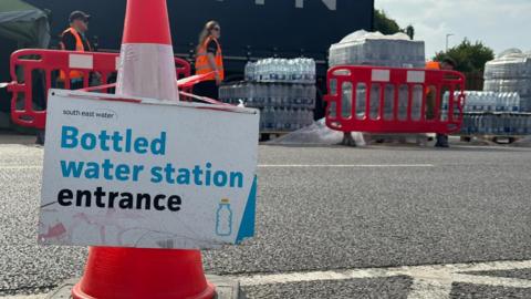 Bottles of water at an emergency outdoor centre in Herne Bay with a sign and cones.