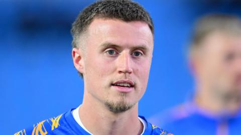 A close-up of George Nurse. He has short dark hair and is wearing a blue and yellow Shrewsbury shirt.