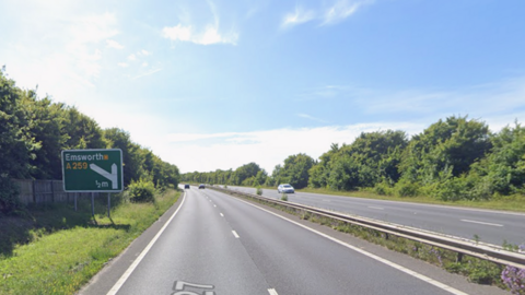A27 dual carriageway with green road sign to Emsworth on the left verge.