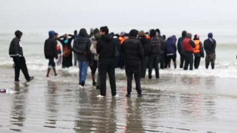 A group of people standing on a beach. 