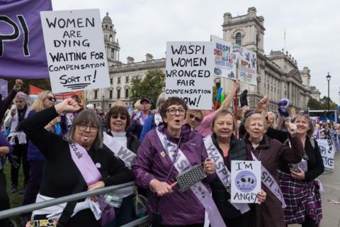 A group of older women hold placards as they chant in protest outside parliament in London in October 2024