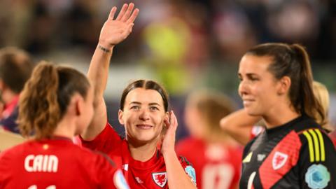 Angharad James, flanked by Hannah Cain and Olivia Clark, waves to fans
