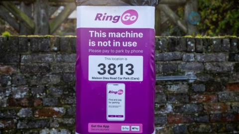 A parking meter covered in a plastic bag, which reads: This machine is not in use. Please pay to park by phone. This location is 3813