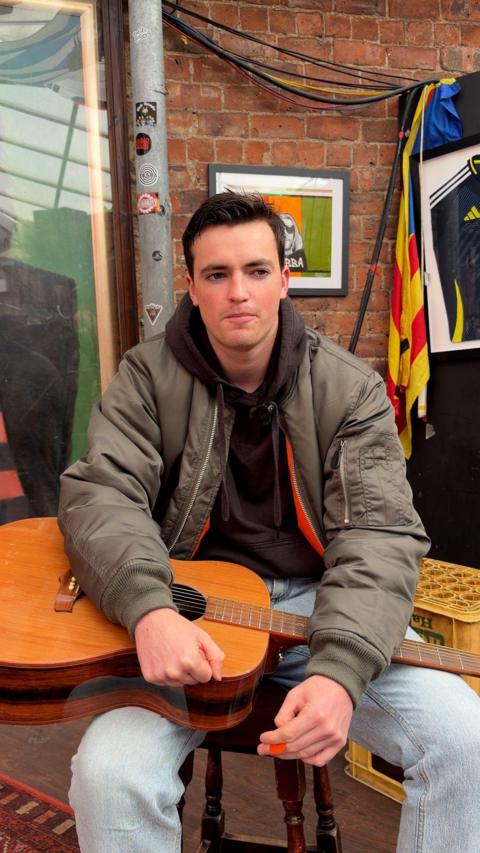Man with dark hair holding guitar