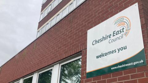View of Cheshire East Council's headquarters, focused on a sign on saying Cheshire East Council welcomes you