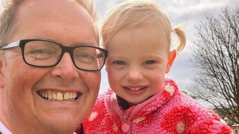 Close-up of Dan Williams, who is wearing glasses, holding his granddaughter.