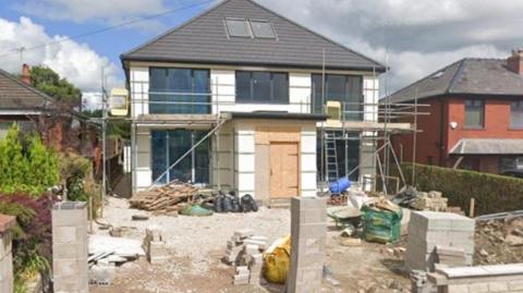 Partially built house with building materials in front of the dwelling