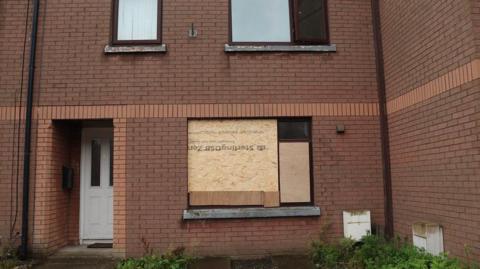 A terraced house in Lindsay Way, south Belfast, with the front window boarded up after bricks were throw at the glass