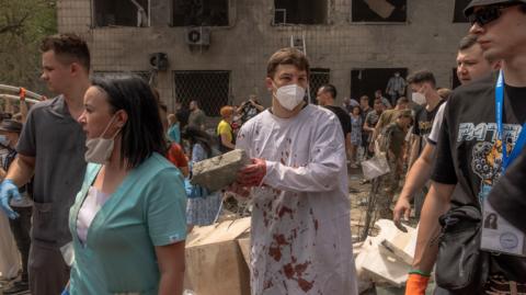 Hospital personnel and volunteers form a human chain to clear the rubble at Kyiv's Ohmatdyt's children's hospital after a missile strike blamed on Russia. Photo: 8 July 2024