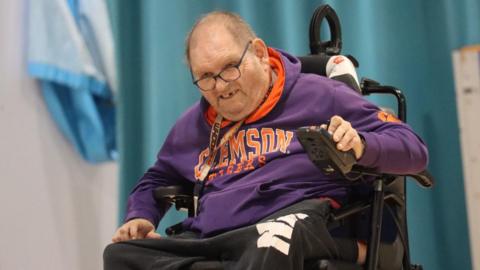 Andy Webb, a man in his 60s, sat in one of the powered wheelchairs used during powerchair football.
