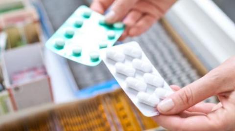 Two strips of medicine are being held above other stocks. The person is holding one strip in each hand.a pac